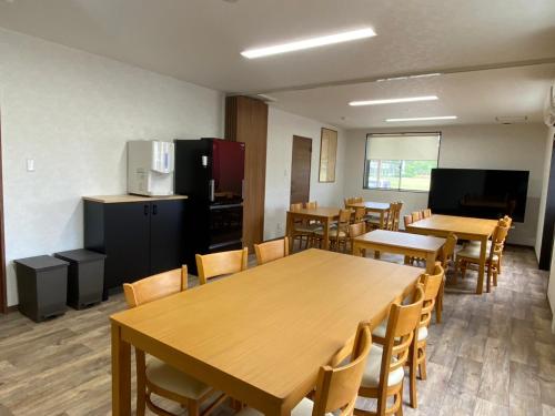 a dining room with tables and chairs and a refrigerator at SWELL in Hyuga