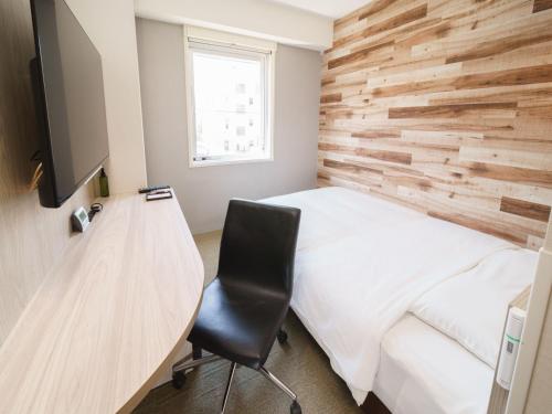a room with a bed and a desk with a chair at Super Hotel Shinbashi-Karasumoriguchi in Tokyo