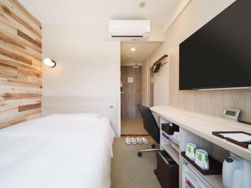 a hotel room with a bed and a flat screen tv at Super Hotel Shinbashi-Karasumoriguchi in Tokyo