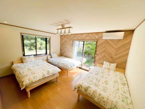伊豆市にあるIzu Serenity Fuji-View Retreat with Private Onsenのベッド2台と窓2つが備わる客室です。
