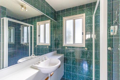 a green tiled bathroom with a sink and a tub at Beach Shack on the Lagoon in Berrara