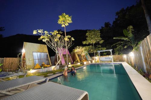 2 personnes assises dans une piscine la nuit dans l'établissement La Vie en Rose, à Senggigi