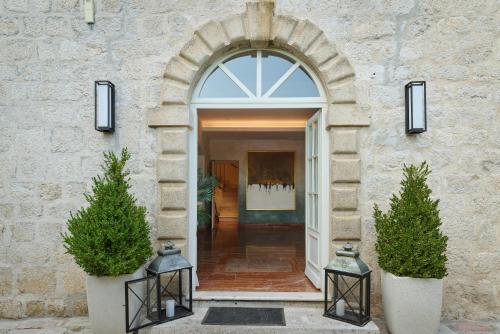 an entrance to a building with two trees in pots at Vila Perast Boutique Hotel in Perast