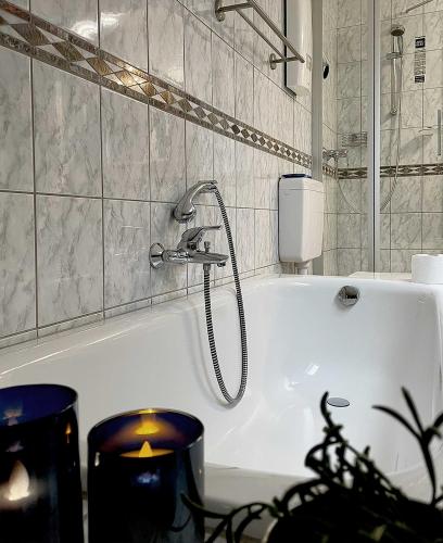 a white bath tub with a shower in a bathroom at Ferienwohnung Taunusurlaub in Hausen über Aar