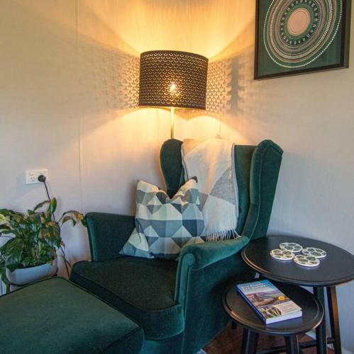 a living room with a green chair and a table at Banksia Cottage, pretty cottage with garden in Leura