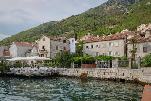 a village on a river with buildings and a mountain at Vila Perast Boutique Hotel in Perast