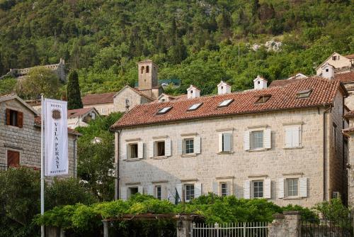 a large stone building with a mountain in the background at Vila Perast Boutique Hotel in Perast