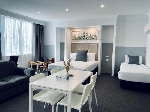 a hotel room with two beds and a table and a couch at The Select Inn Penrith in Penrith