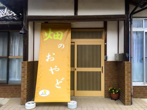 una porta gialla con scrittura cinese sul lato di un edificio di Hatake no Oyado - Vacation STAY 73522v a Takeda