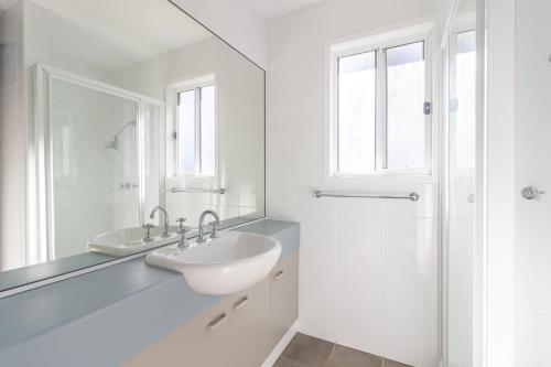 a white bathroom with a sink and a mirror at Berrara Lagoon Front Chalet in Berrara