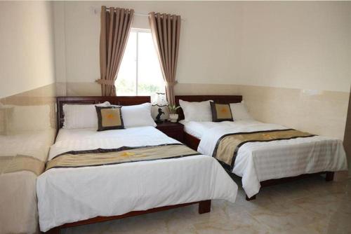 three beds in a room with a window at Magnolia Hotel Cam Ranh in Cam Ranh