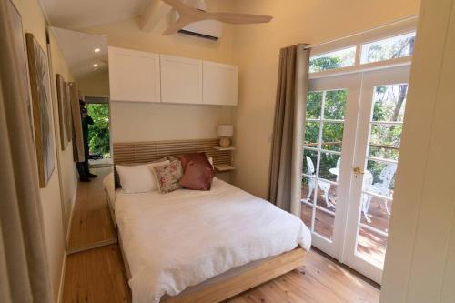 a bedroom with a bed and a large window at Bottlebrush Cabin, cosy private cabin in the trees in Leura