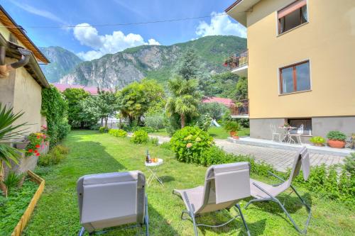 un cortile con sedie e un tavolo con una montagna sullo sfondo di The Bon'Ora Apartment - Happy Rentals a Riva del Garda