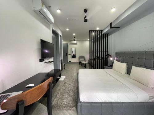 Dormitorio con cama, escritorio y TV en BedChambers Luxurious Serviced Apartment in Gurgaon en Gurgaon