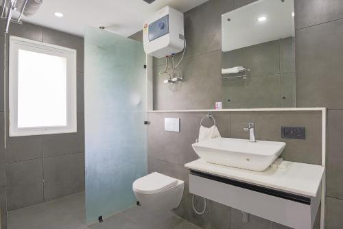 a bathroom with a sink and a toilet and a window at BedChambers Luxurious Serviced Apartment in Gurgaon in Gurgaon
