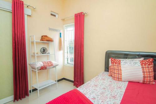 1 dormitorio con 1 cama con cortinas rojas y ventana en Villa Kencana with Balcony Mountain View, en Batu