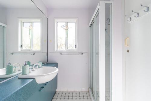 a white bathroom with a sink and a shower at Kangaroo Cabin in Berrara