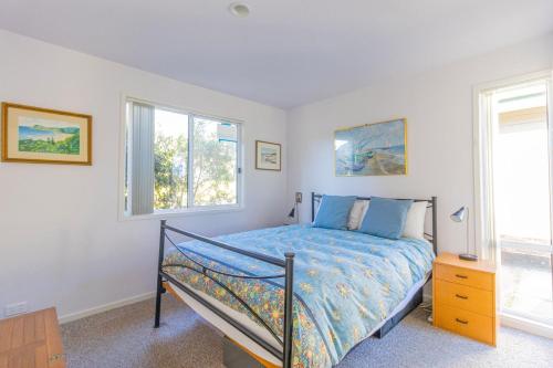 a bedroom with a bed and two windows at Kangaroo Cabin in Berrara