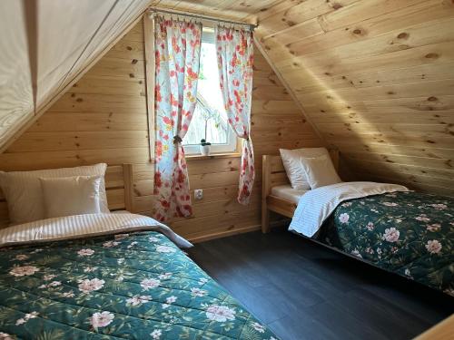 sypialnia z 2 łóżkami w drewnianym domku w obiekcie Domek 4-6osobowy w mieście Wroceń