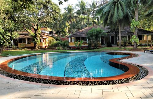 a swimming pool in front of a house with a resort at Granpa's Inn Hotel Bougainvillea in Anjuna