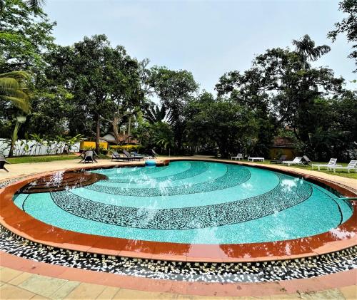 a swimming pool with a fountain in a park at Granpa's Inn Hotel Bougainvillea in Anjuna
