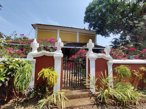 una casa con una valla blanca y flores rosas en Granpa's Inn Hotel Bougainvillea, en Anjuna