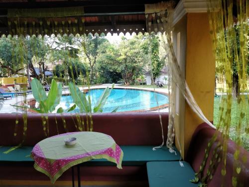 a porch with a table and a swimming pool at Granpa's Inn Hotel Bougainvillea in Anjuna