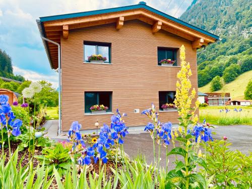 a house with blue flowers in front of it at Woodpecker Chalets in Klösterle am Arlberg