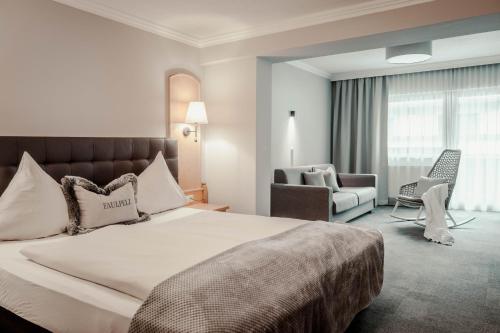 Cette chambre comprend un grand lit et une chaise. dans l'établissement Hotel St. Georg zum See, à Maurach