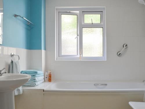 a bathroom with a white sink and a window at Rivendell in Blakeney