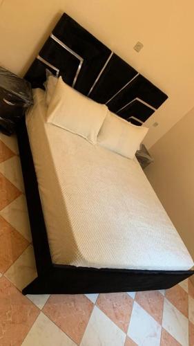 uma cama com cabeceira preta e almofadas brancas em Kornich em Nador