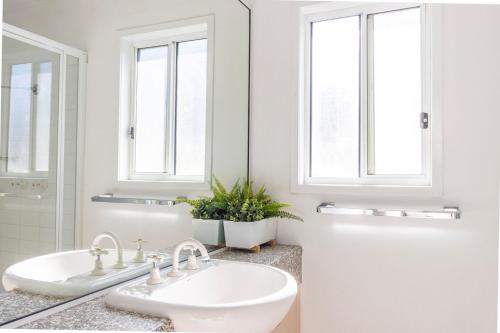 a bathroom with two sinks and two windows at Nannys Beach House in Berrara