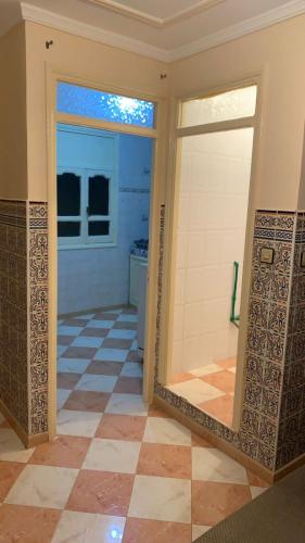 a bathroom with a mirror and a tiled floor at Kornich in Nador