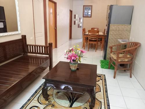 una sala de estar con una mesa con un jarrón de flores. en Ria homestay & kids pool en Alor Setar