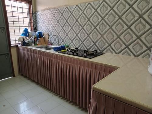 a kitchen counter with a stove and a sink at Ria homestay & kids pool in Alor Setar