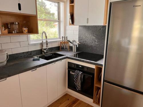 a kitchen with white cabinets and a stainless steel refrigerator at Sunflower House, a cozy cabin at Lake Wentworth in Wentworth Falls