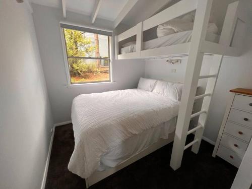 Dormitorio pequeño con litera y ventana en Sunflower House, a cozy cabin at Lake Wentworth, en Wentworth Falls