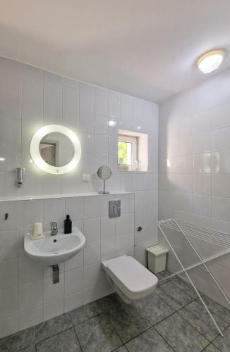 a white bathroom with a toilet and a sink at Szafranówka in Władysławowo