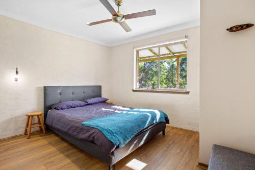 a bedroom with a bed and a ceiling fan at Braeside Cabin One Pinkwood in Central Tilba