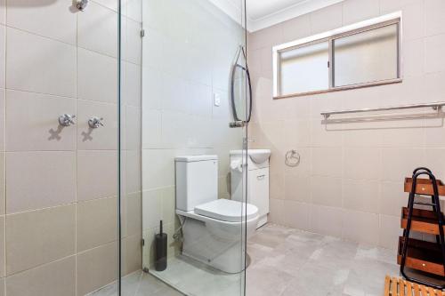 a bathroom with a toilet and a glass shower at Braeside Cabin One Pinkwood in Central Tilba