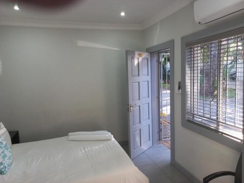 a bedroom with a bed and a window and a door at Triple9 Hatfield Guesthouse in Pretoria