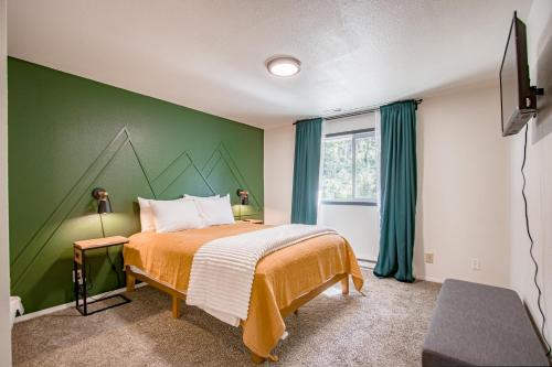 a bedroom with a green accent wall and a bed at Tanglewood Retreat in Post Falls