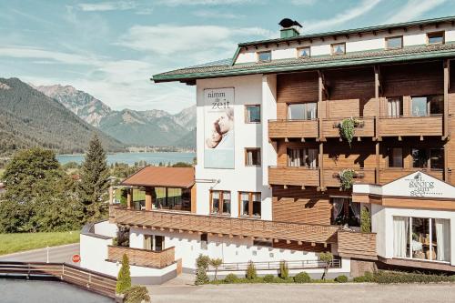 a building with a balcony and mountains in the background at Hotel St. Georg zum See in Maurach