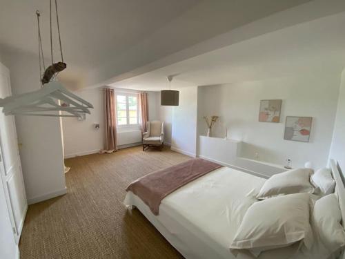 une chambre blanche avec un grand lit et une chaise dans l'établissement Chai Nous ! Maison rénovée sur un domaine viticole proche de Saint Emilion, à Gardegan-et-Tourtirac
