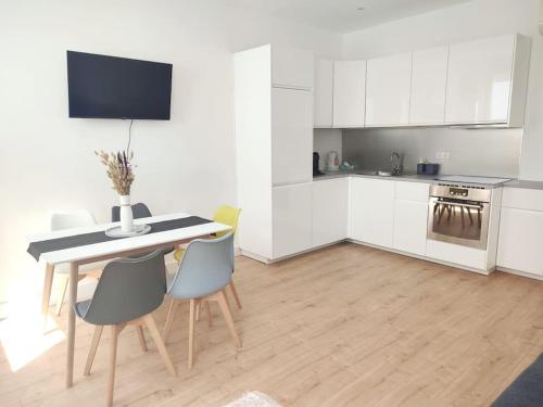 uma cozinha com armários brancos e uma mesa e cadeiras em Appartement Strasbourg Centre em Estrasburgo