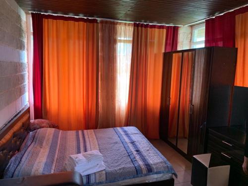 una camera da letto con tende arancioni, un letto e un comò di royal_beach_cottege a Chok-Tal