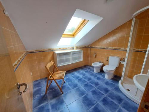 une salle de bains mansardée avec des toilettes et une lucarne. dans l'établissement Casa Antonia Portosín, à Portosín