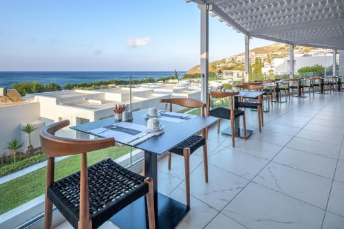 a restaurant with tables and chairs and a view of the ocean at Dimitra Beach Hotel & Suites in Agios Fokas