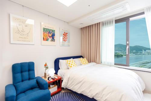 a bedroom with a bed and two blue chairs at Ocean Top Marina in Yeosu