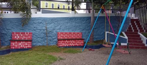 a playground with red and blue bricks and a wall at Serene Blossom Valley in Tenkāsi